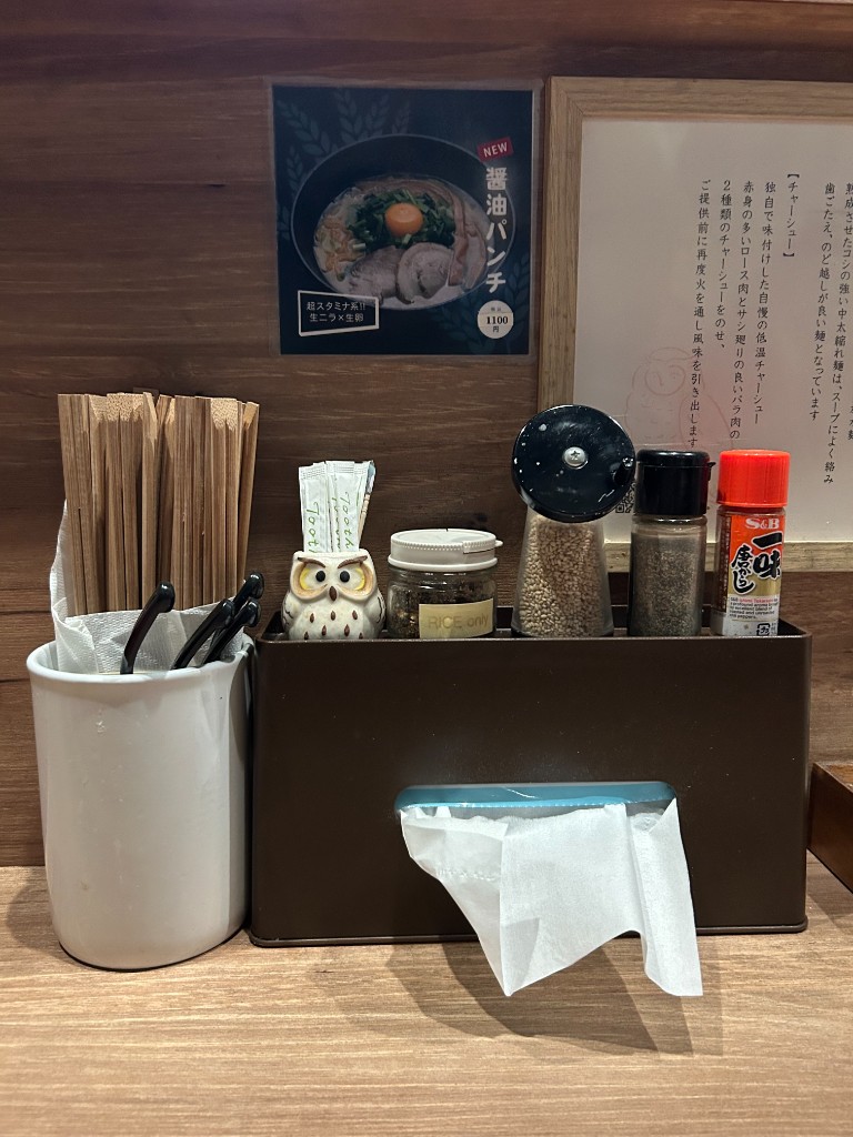 卓上の調味料と梟の置物。背景にメニューポスター(醤油パンチ等)