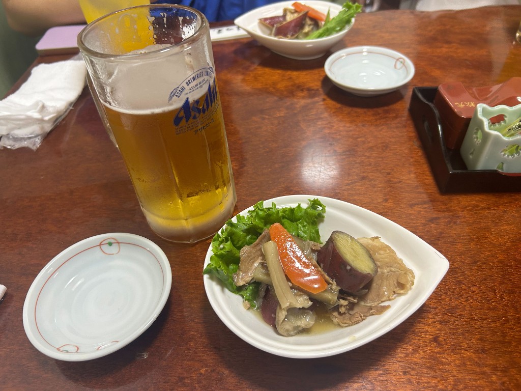 生ビールとお通し風の小鉢。卓上の小物に「まつ元」の表記