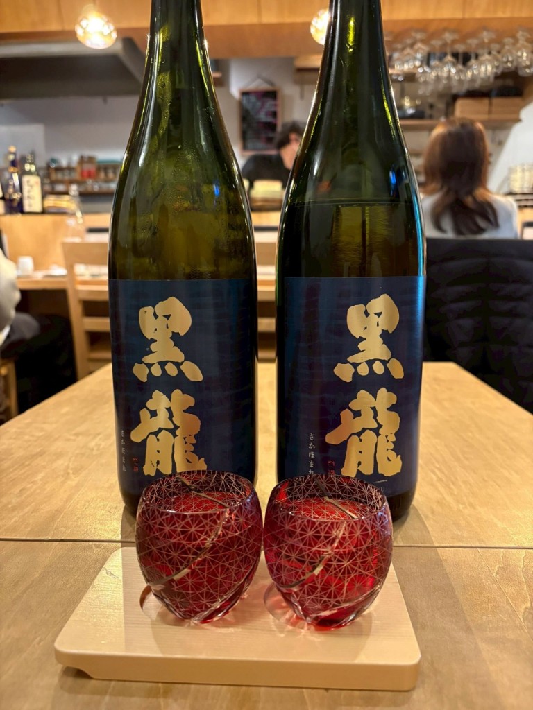黒い盆に並んだ2本の黒龍(こくりゅう)。手前に赤いきりこグラス2脚(酒家 ハル。)
