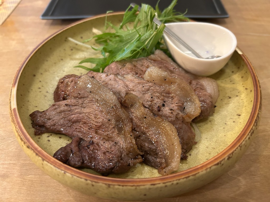 スペックルグリーンの皿に盛られた鹿肉のソテー。薄切りで火入れ加減が絶妙。水菜と白いソースが添えられる(酒家 ハル。)
