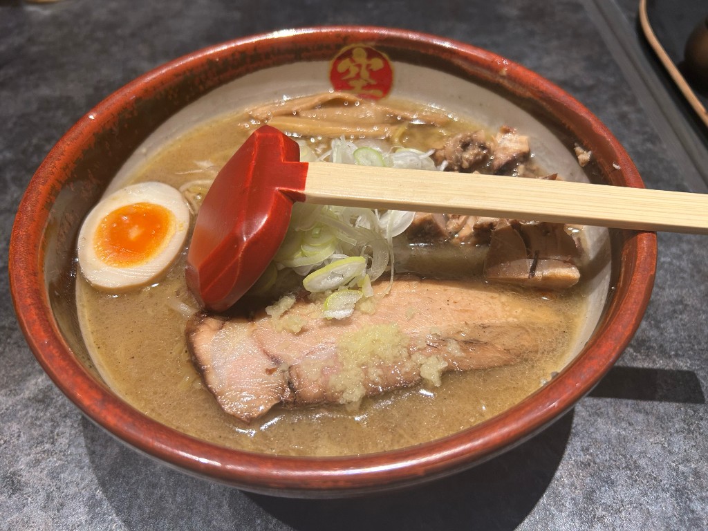 深い器に盛られた味噌ラーメン。とろけるチャーシュー、半熟玉子、メンマ、白髪ネギ、赤い色合いのアクセント。スープは濃厚な黄金色(らーめん空)